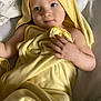 baby, infant, child, hooded_towel, yellow_towel, towel_wrap, bed, pillow, blanket, hand, blue_eyes, smile, portrait, indoors, cozy, soft_texture, skin, close_up, screenshot, relaxed