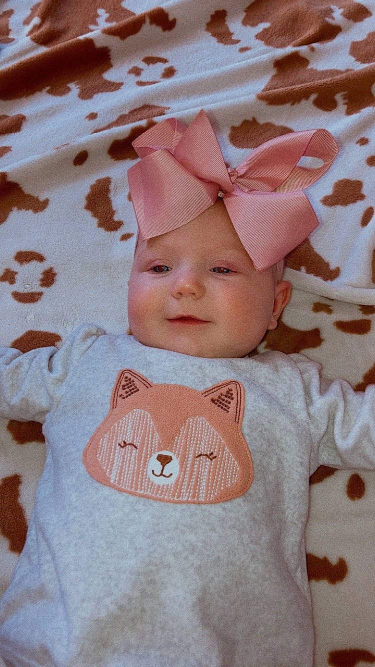 Oaklee is registered to the contest to win money with this photo: baby, baby_toddler_clothing, cap, cheek, child, collar, eye, face, headgear, headwear, linens, lip, pattern, peach, person, pink, product, skin, sleeve, textile