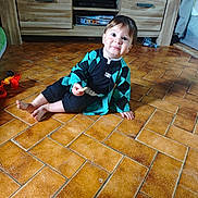 Maïlo participe au concours pour gagner de l'argent avec cette photo : barefoot, black_clothing, cabinet, child, curious, cute, floor, furniture, home, indoor, person, portrait, sitting, smile, snack, teal_clothing, tile, toddler, toy, young_child