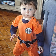 Maïlo joined the competition — help win amazing prizes! toddler, child, standing, orange_outfit, anime_costume, indoors, floor_tiles, barefoot, face, short_hair, playpen, furniture, cabinet, curious, young_child, person, home, portrait, looking_at_camera, cute