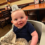 Waylon joined the competition — help win amazing prizes! baby, blanket, blue_shirt, chairs, cute, food, glitter_hat, half_birthday, half_hat, happy, highchair, indoor, infant, meat, messy_face, plush_blanket, portrait, restaurant, smiling, table