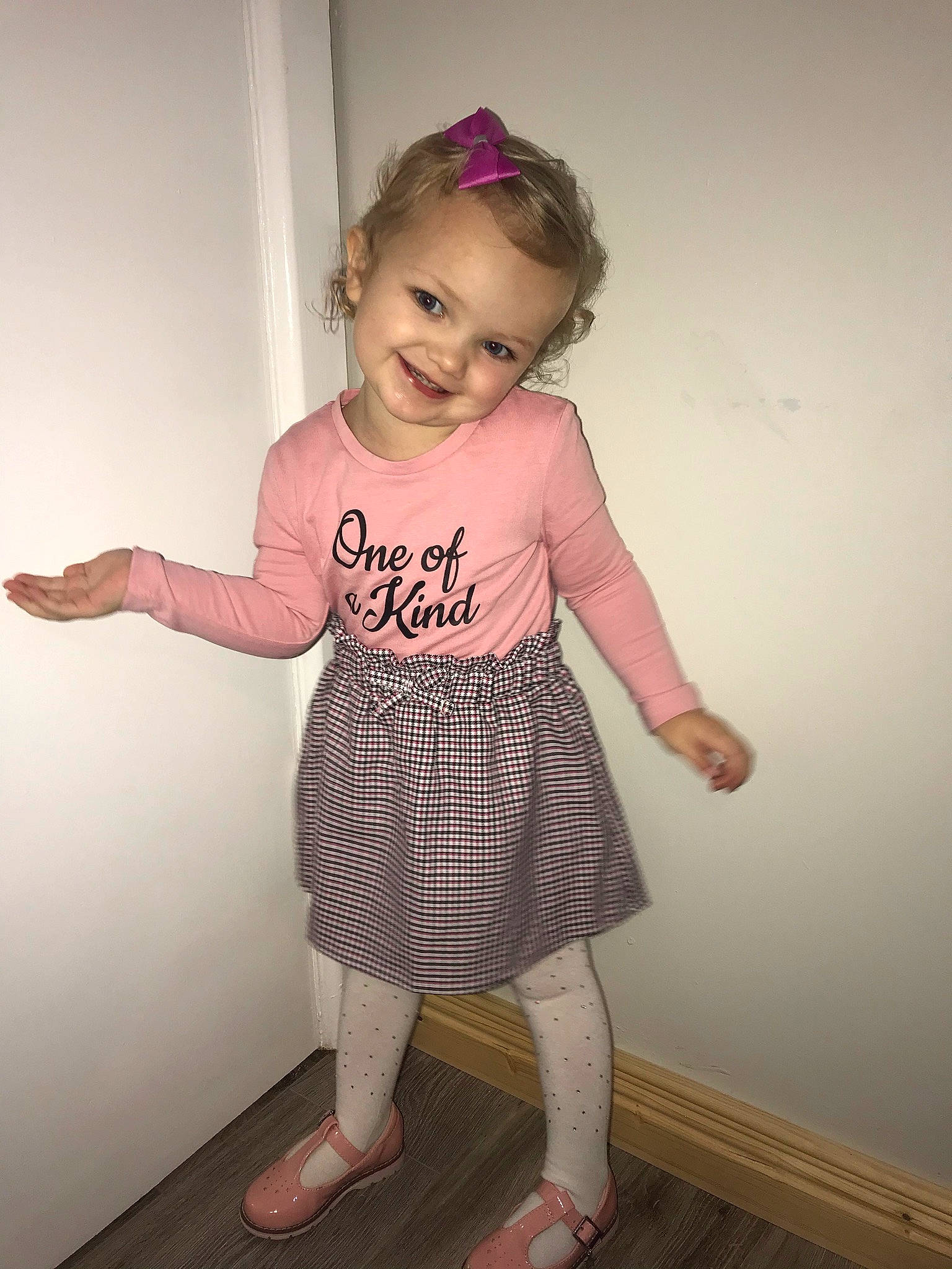 Lilly-rose is registered to the contest to win money with this photo: ankle, baby, baby_toddler_clothing, child, day_dress, floor, foot, hair_accessory, joint, joy, magenta, one_piece_garment, pattern, person, pink, purple, shoulder, sleeve, slipper, standing