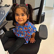 Sarai Lopez joined the competition — help win amazing prizes! child, girl, pigtails, smile, blue_dress, butterfly_pattern, black_chair, office_chair, indoor, floor, white_wall, black_leggings, white_shoes, happy, portrait, person, furniture, cute, seated, young