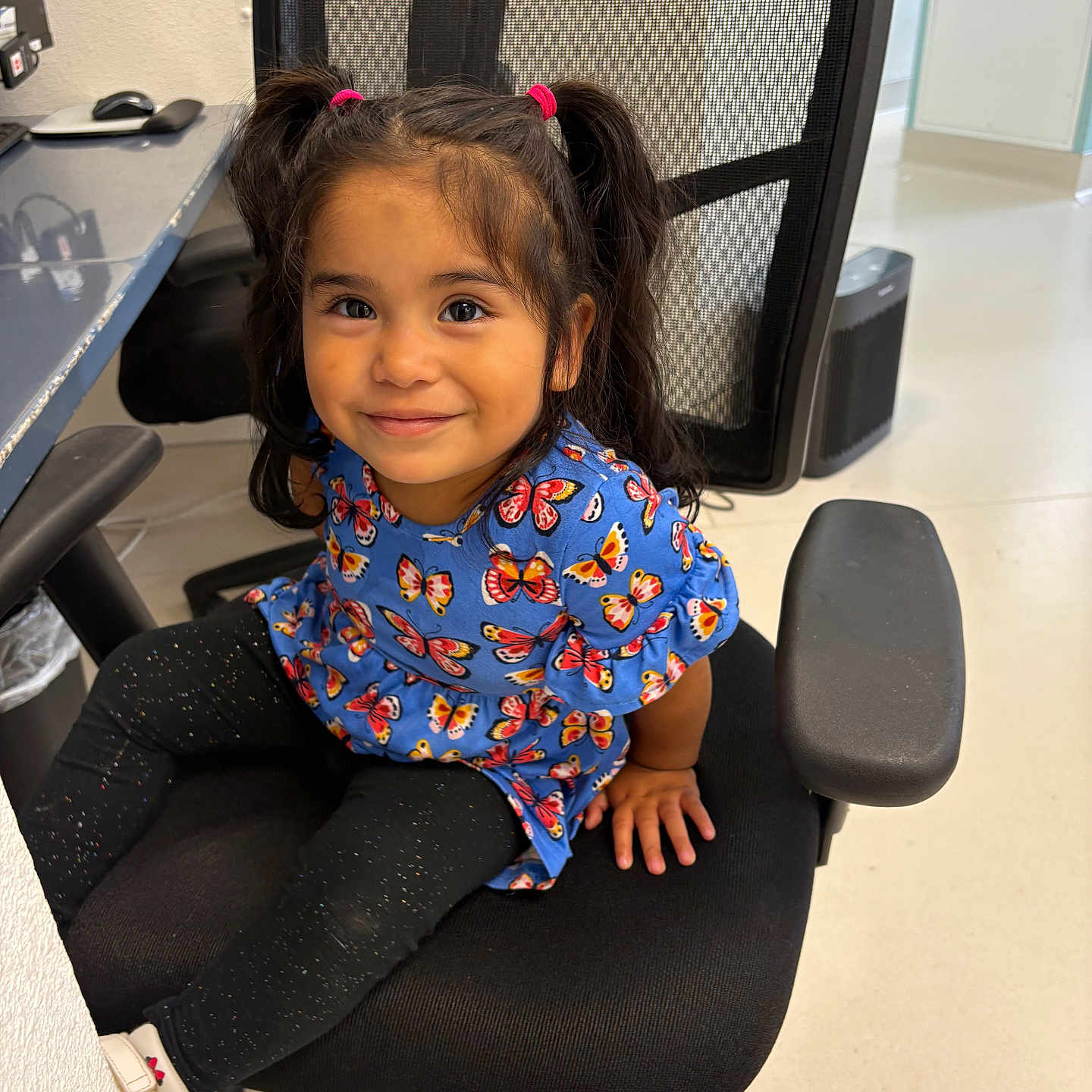 Sarai Lopez joined the competition — help win amazing prizes! black_chair, black_leggings, blue_dress, butterfly_pattern, child, cute, floor, furniture, girl, happy, indoor, office_chair, person, pigtails, portrait, seated, smile, white_shoes, white_wall, young