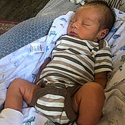 Ronnie joined the competition — help win amazing prizes! baby, newborn, sleeping, striped_onesie, white_socks, blanket, dinosaur_print, pillow, home_interior, floor, wood_floor, carpet, infant, cute, resting, child, clothing, soft_texture, peaceful, portrait
