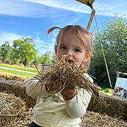 Angelina a rejoint le concours — aidez-le/la à gagner de superbes lots ! child, toddler, straw, outdoor, play_area, pigtails, grass, trees, blue_sky, canopy, happy, smiling, nature, sunlight, casual_clothing, person, daytime, fun, holding, playtime