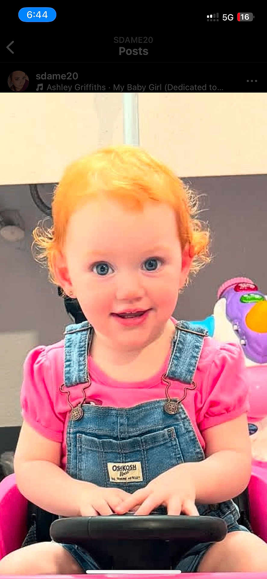 Kinslee joined the competition — help win amazing prizes! child, toddler, red_hair, blue_eyes, denim_overalls, pink_shirt, toy_car, steering_wheel, indoor, smiling, cute, curly_hair, playtime, baby, person, young_child, happy, seat, hands, face