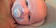 Jaxson is registered to the contest to win money with this photo: baby, pacifier, infant, face, head, eyes, clothing, blanket, cushion, crib, playpen, indoor, closeup, resting, young_child, child, soft_lighting, sleeping_area, comfort, portrait