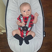 Jaxson joined the competition — help win amazing prizes! baby, infant, onesie, red_clothing, black_socks, baby_seat, safety_harness, wood_floor, indoor, person, cute, looking_at_camera, wide_eyes, small_hands, footwear, plush_seat, child, home, flooring, casual
