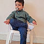 Souleyman participe au concours pour gagner de l'argent avec cette photo : child, pacifier, chair, sweater, pants, sock, indoor, floor, wall, plastic_chair, person, seated, crossed_legs, young_child, curious_expression, casual_clothing, short_hair, light_skin, home, portrait
