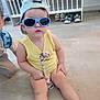 accessory, baby, cap, carpet, child, crib, cute, floor, furniture, glasses, headwear, indoor, kid, pacifier_clip, person, shoes, sitting, sunglasses, toddler, yellow_clothing