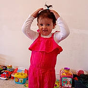 Amina is registered to the contest to win money with this photo: toddler, child, pink_romper, toy, carpet, indoor, playtime, smiling, hair_tie, colorful, room, young_child, person, cute, happy, casual, standing, fun, messy, playroom