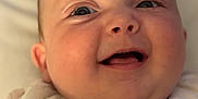 Freya is registered to the contest to win money with this photo: baby, close_up, smile, face, infant, child, cute, expression, soft, white_clothing, portrait, happy, skin, eyes, mouth, cheeks, newborn, indoors, head, young