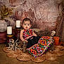 Vedaa joined the competition — help win amazing prizes! baby, child, traditional_clothing, colorful_dress, sitting, wooden_chair, candles, dried_plants, woven_mats, rustic, boho_style, decor, portrait, indoor, cute, expression, bracelet, floor, background, furniture