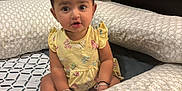 Vedaa joined the competition — help win amazing prizes! toddler, child, baby, yellow_dress, butterfly_pattern, bracelet, earrings, cushion, bed, indoor, person, furniture, floor, looking, sitting, cute, curious, young_child, home, expression