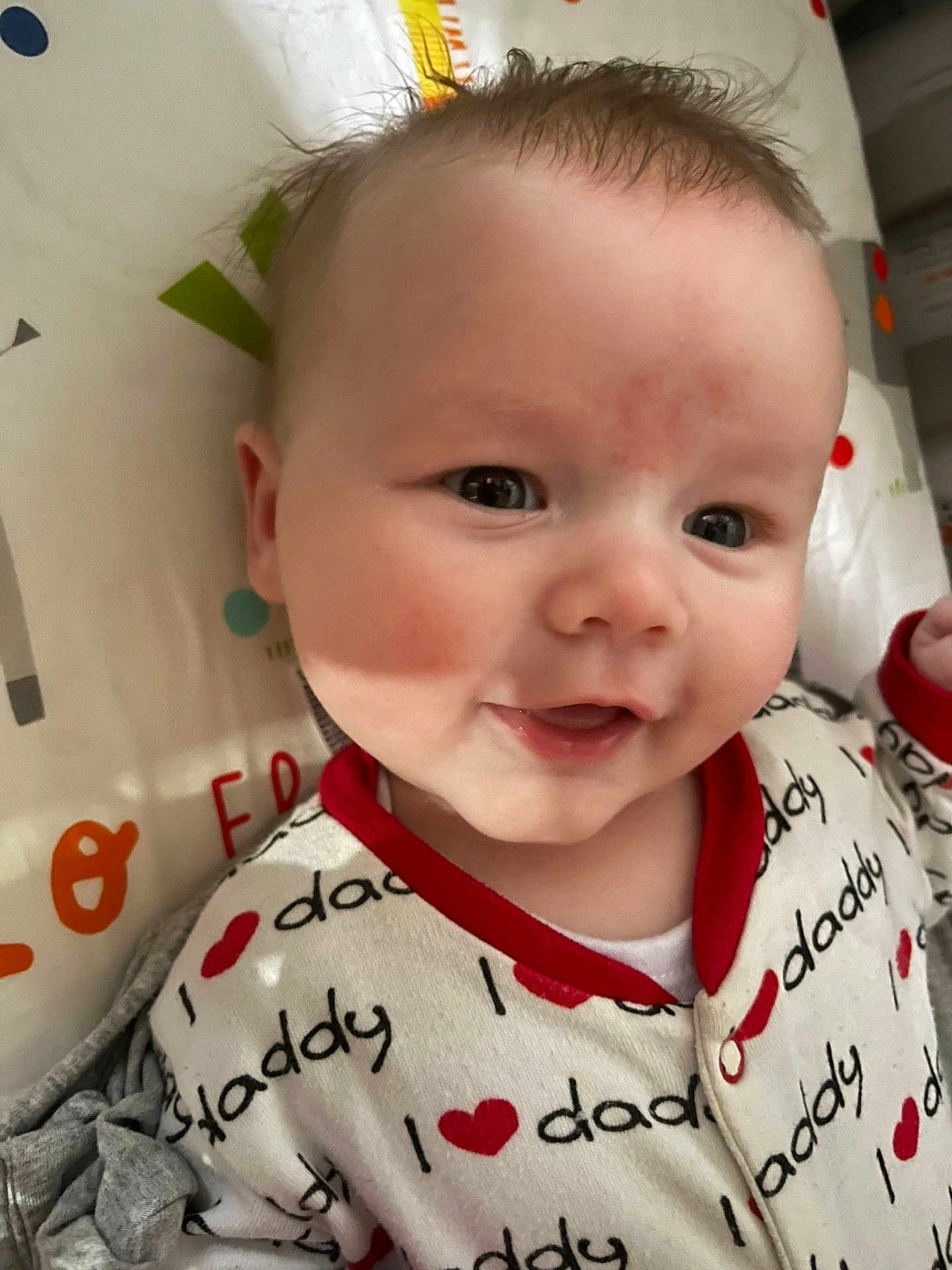 Luka joined the competition — help win amazing prizes! baby, infant, smiling, face, clothing, red_trim, text_print, pattern, close_up, cute, child, skin, head, eyes, mouth, background, fabric, happy, indoors, person