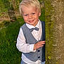 child, boy, smiling, outdoor, tree, grass, vest, bow_tie, white_shirt, portrait, nature, happy, cute, young_child, blond_hair, casual, playful, greenery, person, fashion