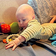 Wes is registered to the contest to win money with this photo: baby, bed, blanket, child, couch, curious, expression, face, focus, hand, indoor, infant, light, pillow, playing, skin, soft_toys, striped_clothing, toy, window
