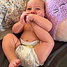 baby, diaper, foot, hand, face, pillow, plush_toy, purple, bed, floral_pattern, skin, cute, child, infant, smiling, lying_down, indoors, happy, toddler, playful