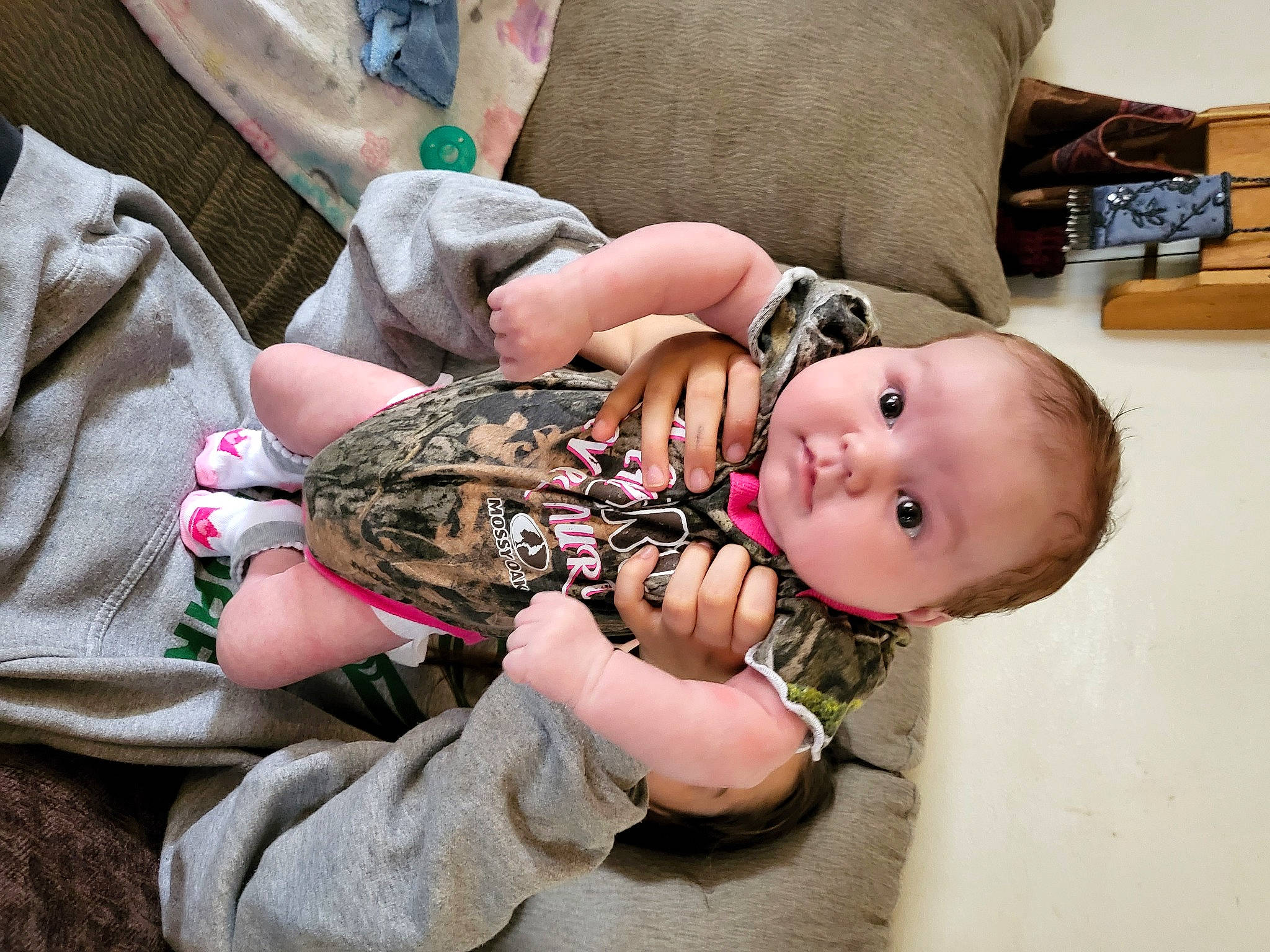 Aleah is registered to the contest to win money with this photo: baby, baby_toddler_clothing, cheek, child, comfort, eyelash, eyewear, flesh, human_leg, military_camouflage, nail, pattern, person, sitting, skin, sleeve, thigh, thumb, toddler, wood
