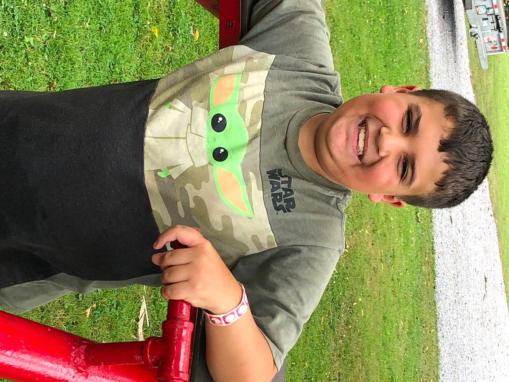 Gavin is registered to the contest to win money with this photo: child, fun, grass, grass_family, green, happy, human_body, human_leg, joint, joy, lawn, leaf, leisure, people_in_nature, person, plant, recreation, red, sitting, smile