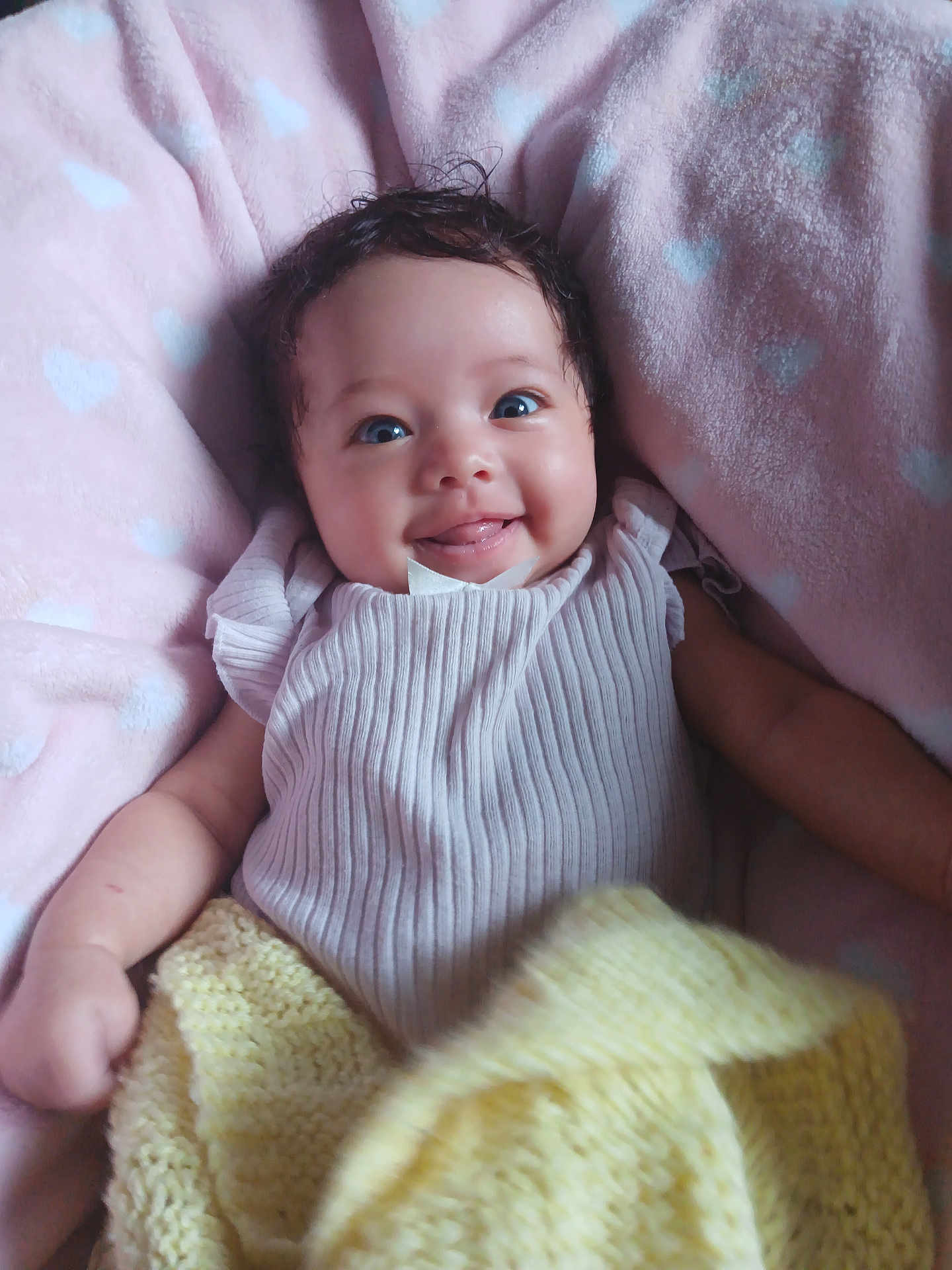 Avianna joined the competition — help win amazing prizes! baby, smiling, tongue_out, pink_blanket, yellow_blanket, cozy, cute, infant, happy, face, child, knit_blanket, soft_texture, lying_down, indoors, adorable, portrait, small_hands, clothing, heart_pattern