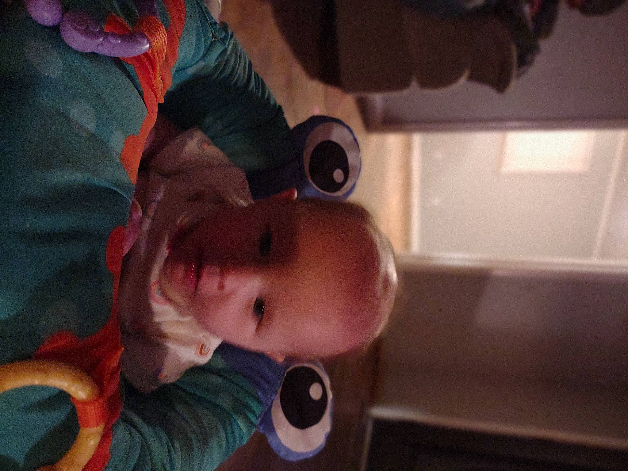 Kathleen is registered to the contest to win money with this photo: arm, audio_equipment, baby, baby_products, cheek, child, finger, fun, headgear, mouth, nose, person, personal_protective_equipment, room, sitting, smile, suit, toddler, tree, vehicle_door