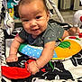 Phoenix is registered to the contest to win money with this photo: baby, infant, playmat, toy, colorful, smiling, cute, child, indoors, plush_toys, face, hand, clothing, patterned, floor, person, happy, toddler, play, crawling