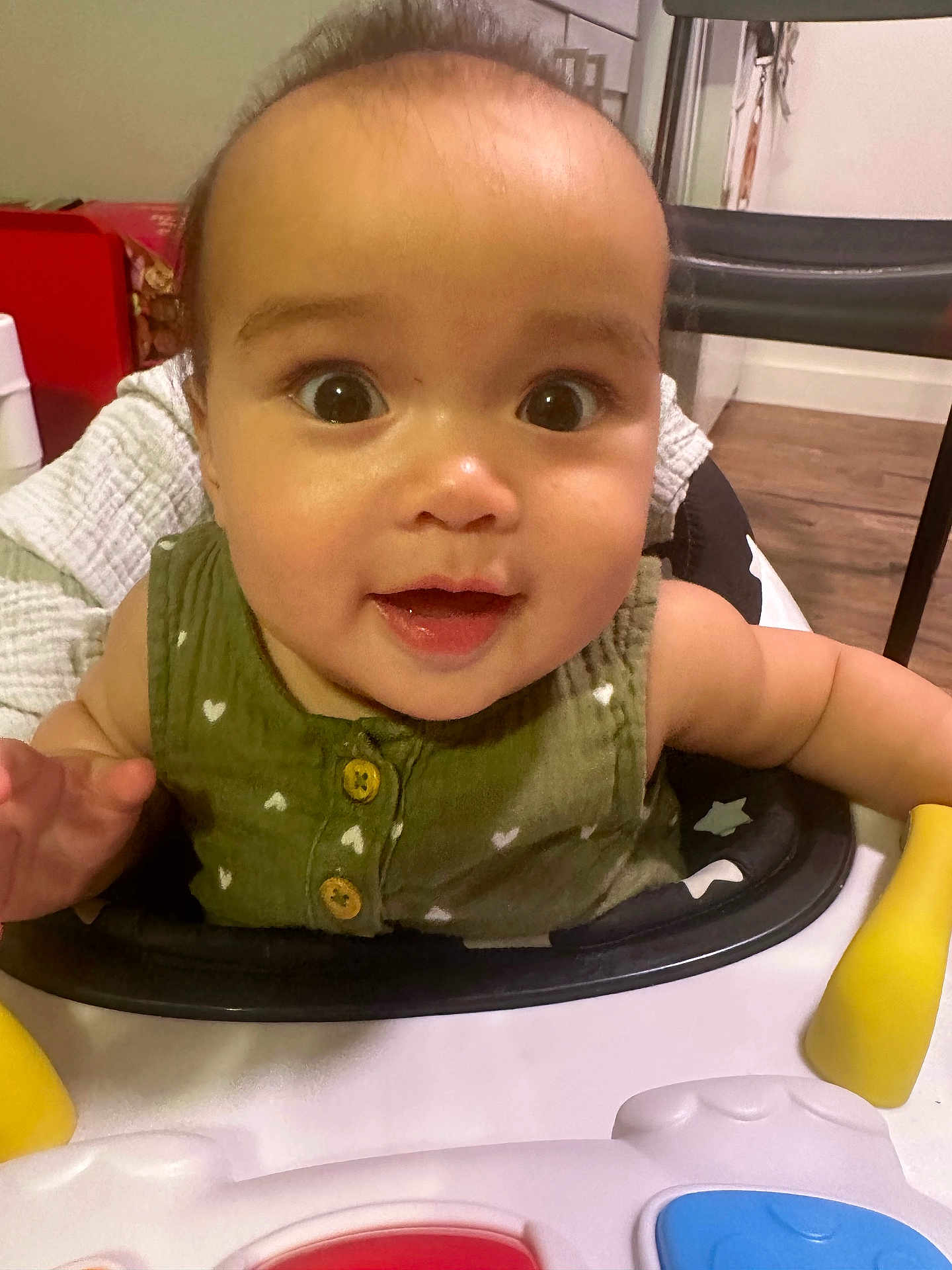 Phoenix joined the competition — help win amazing prizes! baby, child, face, smile, eyes, green_clothing, walker, indoor, toy, curious, cute, happy, infant, person, closeup, skin, sitting, wood_floor, home, furniture