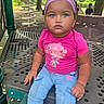 child, toddler, playground, pink_shirt, blue_jeans, headband, curly_hair, outdoor, park, play_equipment, metal_structure, serious_expression, sitting, daylight, trees, greenery, cute, young_child, casual_clothing, person