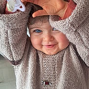 Mélina participe au concours pour gagner de l'argent avec cette photo : baby, blue_eyes, child, cozy, cute, expression, face, hair, hand, happy, indoors, knit_sweater, pacifier, person, playful, portrait, skin, smiling, toddler, warm_clothing