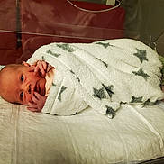 Maya a rejoint le concours — aidez-le/la à gagner de superbes lots ! newborn, baby, blanket, hospital, bassinet, infant, wrapped, face, hand, sleeping_area, soft, stars, cute, lying_down, skin, young_child, portrait, indoor, resting, peaceful