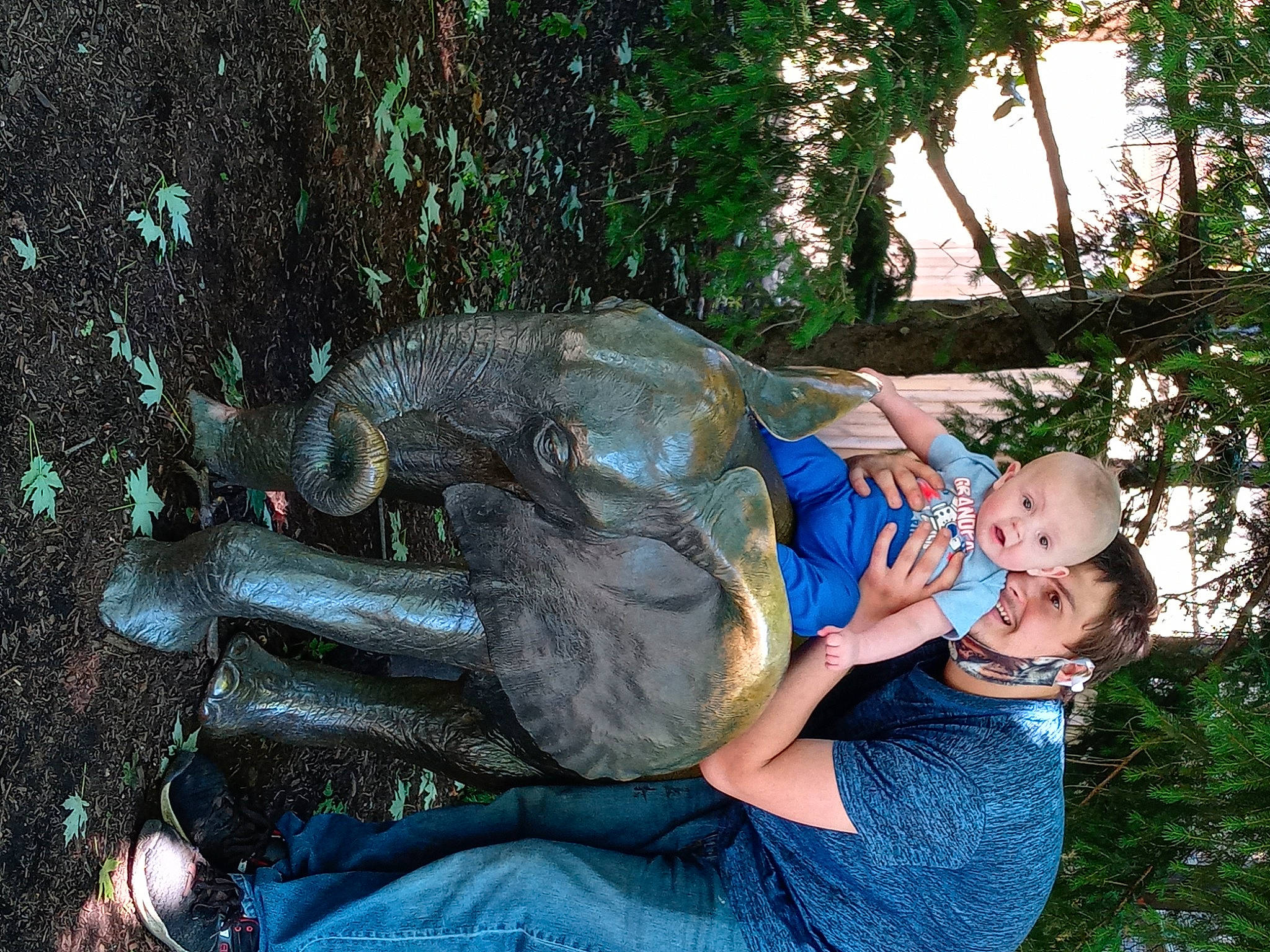 Christopher is registered to the contest to win money with this photo: baby, electric_blue, event, fun, garden, grass, happy, joy, lap, lawn_ornament, leisure, person, plant, recreation, reptile, sitting, smile, sporting_group, tree