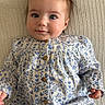baby, child, infant, face, blue_eyes, dress, floral_pattern, buttons, hand, blanket, texture, portrait, cute, smile, lying_down, clothing, skin, hair, young, person