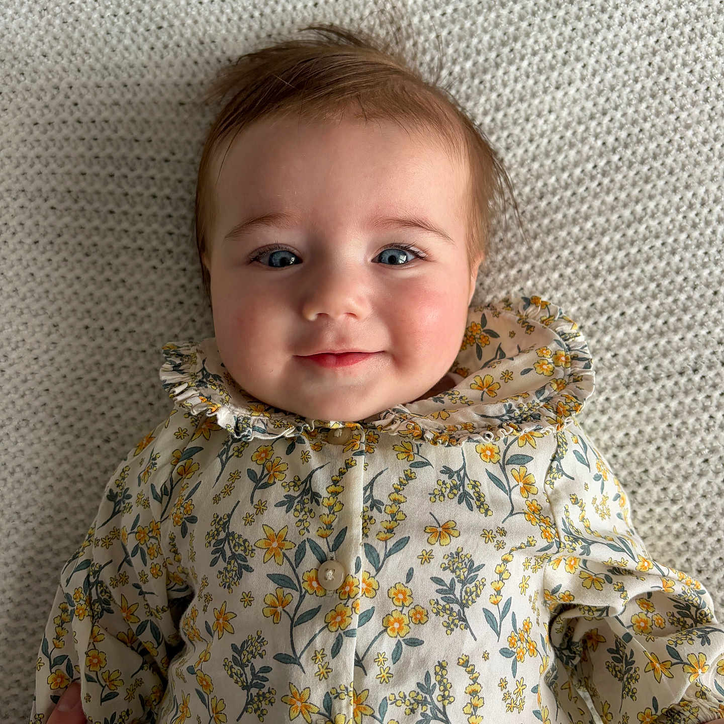 Esmee participe au concours pour gagner de l'argent avec cette photo : baby, infant, face, blue_eyes, smile, floral_clothing, patterned_outfit, texture, blanket, portrait, cute, child, person, laying_down, soft_lighting, hand, happy, indoors, young_child, closeup