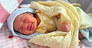 Saturn is registered to the contest to win money with this photo: newborn, baby, smiling, blanket, yellow_blanket, blue_hat, sleeping, cozy, pink_blanket, polka_dots, infant, cute, resting, soft_texture, bed, portrait, child, indoors, comfort, peaceful