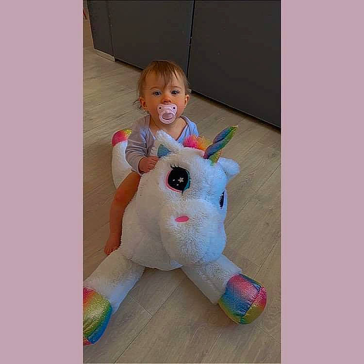 Lily participe au concours pour gagner de l'argent avec cette photo : baby, baby_products, baby_toddler_clothing, baby_toys, fawn, fictional_character, font, happy, magenta, person, play, plush, room, sitting, sleeve, smile, stuffed_toy, t_shirt, toddler, toy