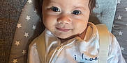 Khalil is registered to the contest to win money with this photo: baby, child, infant, smile, face, eyes, hair, onesie, clothing, seat, cushion, star_pattern, indoor, portrait, straps, pacifier, happy, closeup, cute, young