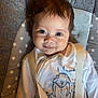 baby, child, infant, smile, face, eyes, hair, onesie, clothing, seat, cushion, star_pattern, indoor, portrait, straps, pacifier, happy, closeup, cute, young