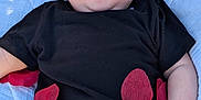 Wyatt is registered to the contest to win money with this photo: baby, infant, child, black_shirt, red_shorts, red_petals, blanket, outdoor, grass, cute, face, hand, skin, expression, lying_down, clothing, summer, casual, playful, portrait