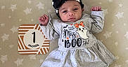 Tessa joined the competition — help win amazing prizes! baby, blanket, bow, child, clothing, cute, ghost_pattern, grey_dress, halloween, headband, holiday_theme, indoors, infant, lying_down, milestone, one_month, pants, portrait, sign, star_pattern