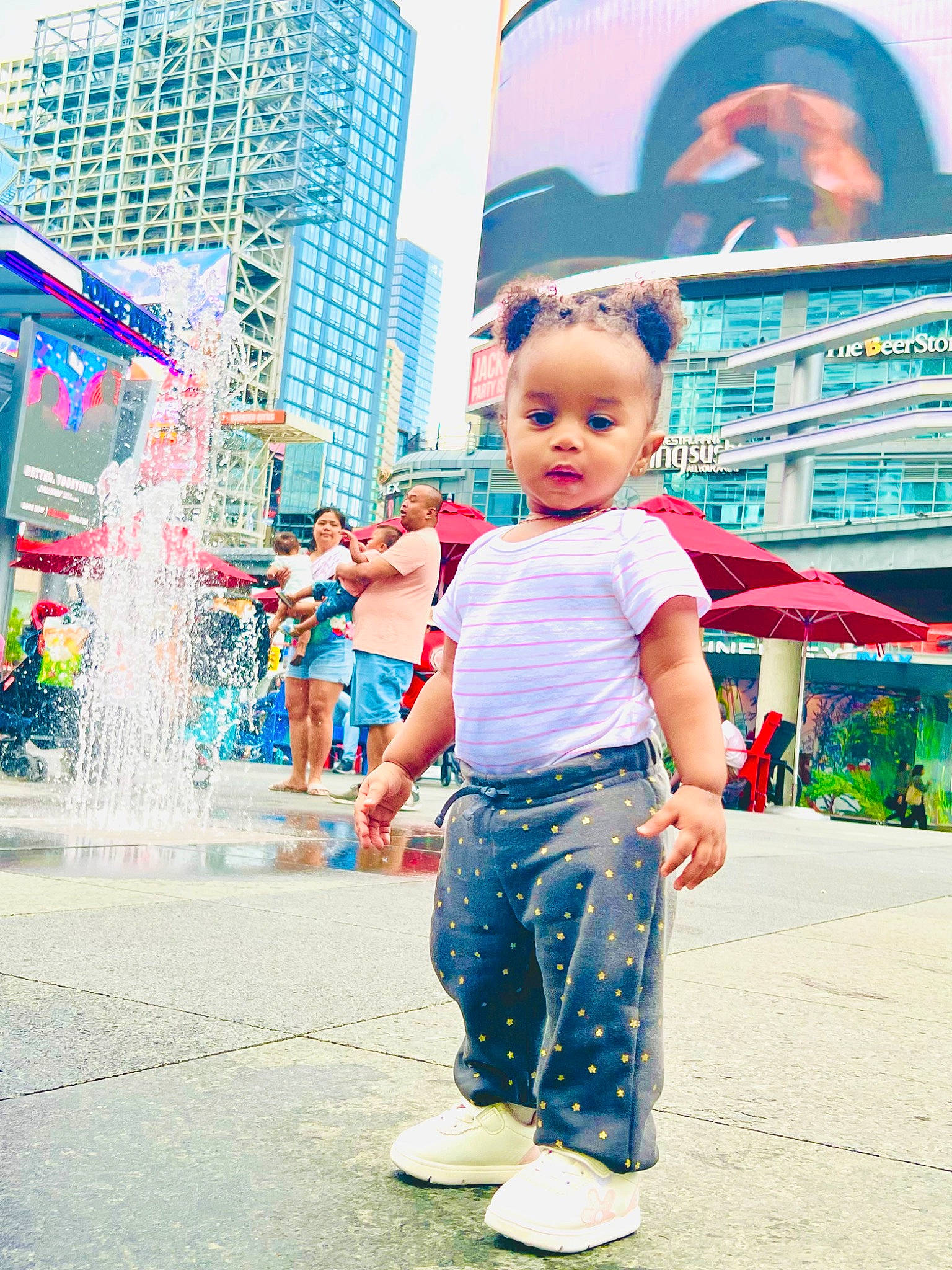 Aaliyah is registered to the contest to win money with this photo: azure, building, child, city, electric_blue, fountain, fun, happy, human, leisure, magenta, pedestrian, person, pink, recreation, sky, standing, street, t_shirt, toddler
