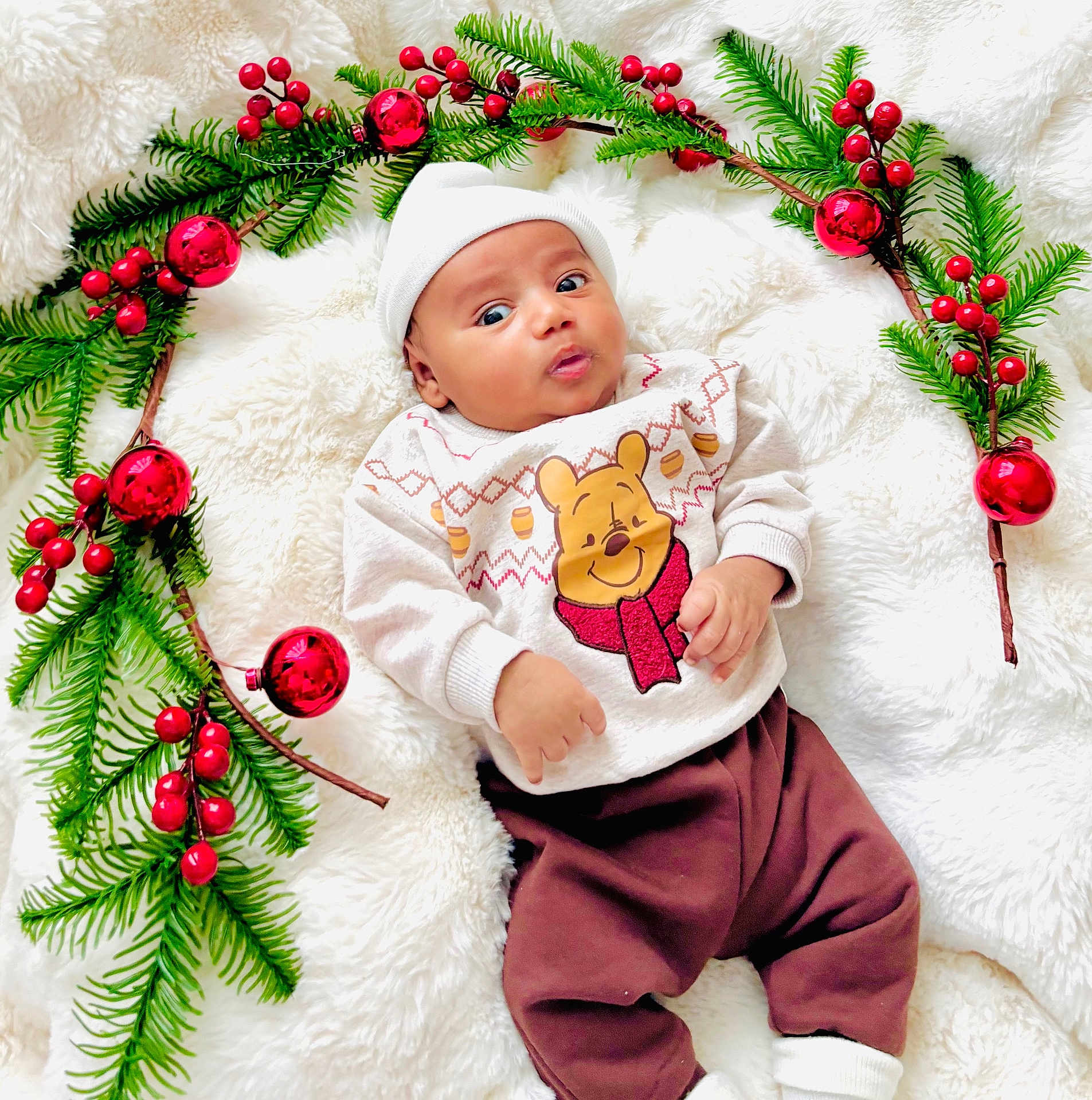 Amal joined the competition — help win amazing prizes! baby, infant, child, white_hat, sweater, brown_pants, blanket, pine_branches, red_ornaments, holiday, christmas, festive, cozy, cute, portrait, indoor, soft_texture, smiling, holiday_decor, winter_clothing