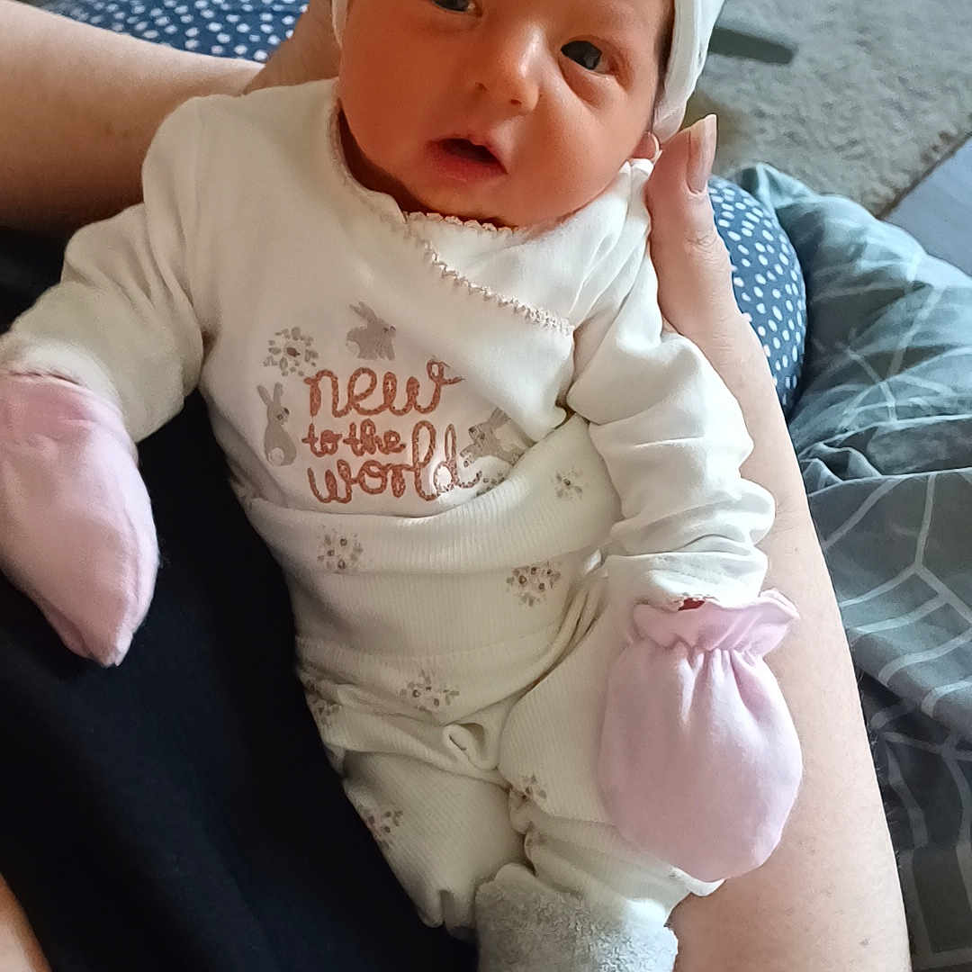 Courtney is registered to the contest to win money with this photo: baby, bodypart, bonnet, cap, clothing, couch, cushion, face, finger, furniture, hand, hat, head, hosiery, newborn, pants, person, photography, portrait, sock