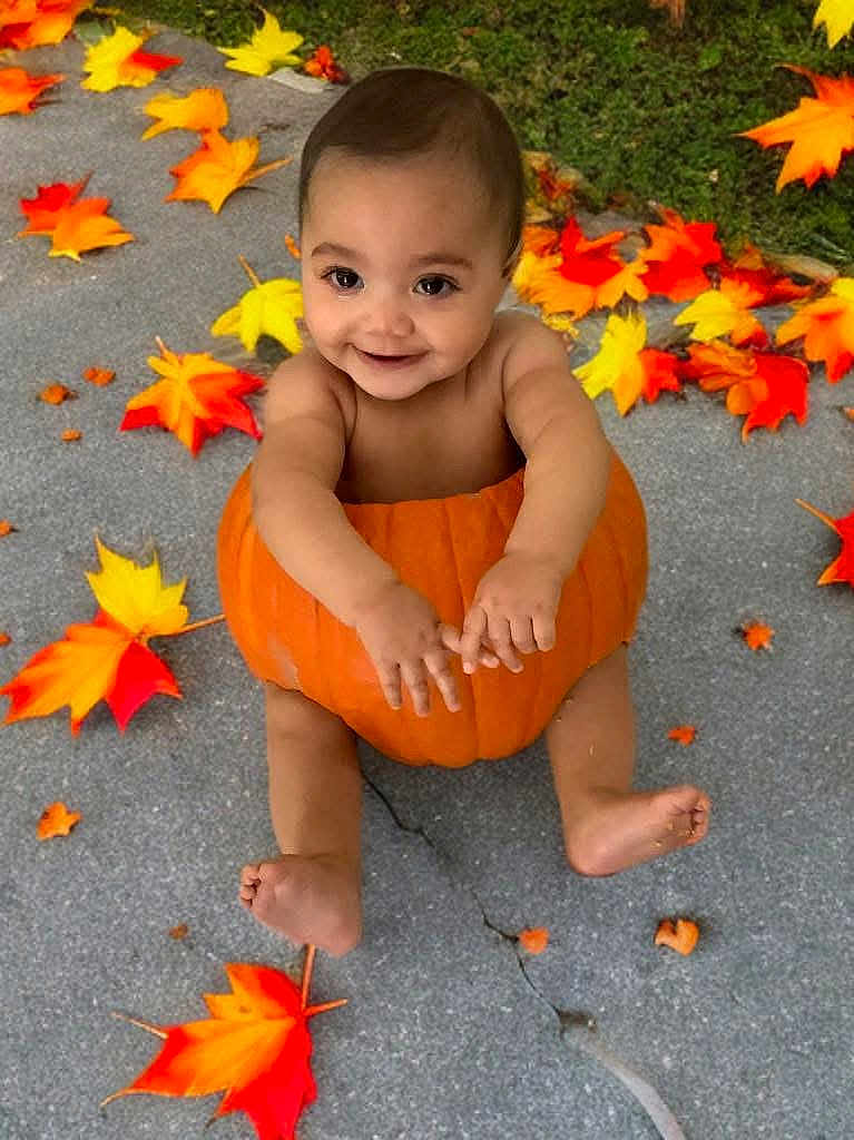 Koda is registered to the contest to win money with this photo: baby, pumpkin, autumn_leaves, fall, outdoor, child, smiling, concrete, seasonal, cute, holiday, nature, orange, yellow, red, barefoot, sitting, festive, happy, portrait