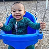 baby, blue_seat, bucket_swing, casual_clothing, child, grass, gripping, happy, infant, joy, outdoor, playground, playground_equipment, portrait, safety_harness, smiling, swing, teal_outfit, teeth, wood_chips