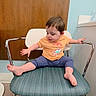 Mia joined the competition — help win amazing prizes! toddler, child, chair, orange_shirt, blue_pants, barefoot, indoor, waiting_room, floor, wood_panel, metal_armrest, curious, sitting, young_child, person, furniture, head, face, short_hair, casual_clothing