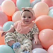 Mia is registered to the contest to win money with this photo: baby, child, balloons, pastel_colors, headband, bow, smiling, sitting, floral_pattern, bib, shoes, cute, happy, indoor, portrait, infant, playful, soft_colors, celebration, decor