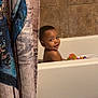 bath_mat, bath_time, bathroom, bathtub, child, curious, cute, face, home, indoor, playful, portrait, shower_curtain, skin, smiling, tile_wall, toddler, toy, water, young_child