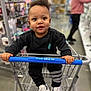 Nyairr joined the competition — help win amazing prizes! toddler, shopping_cart, store, child, black_clothing, sneakers, handlebar, five_below, indoor, person, curly_hair, expression, retail, aisle, blurred_background, holding, footwear, casual, shopping, cute